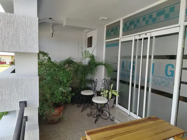 Terraza de acceso con sillas y puerta de vidrio con el logo del instituto